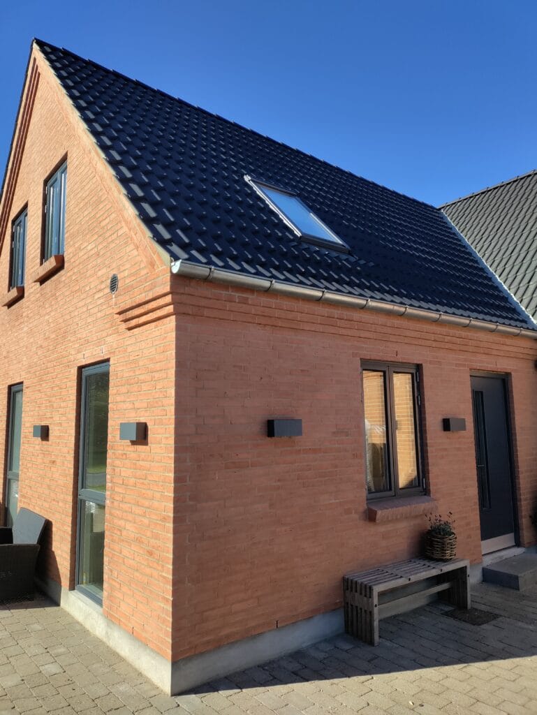 Moderne murstenshus med sort tegltag og ovenlys